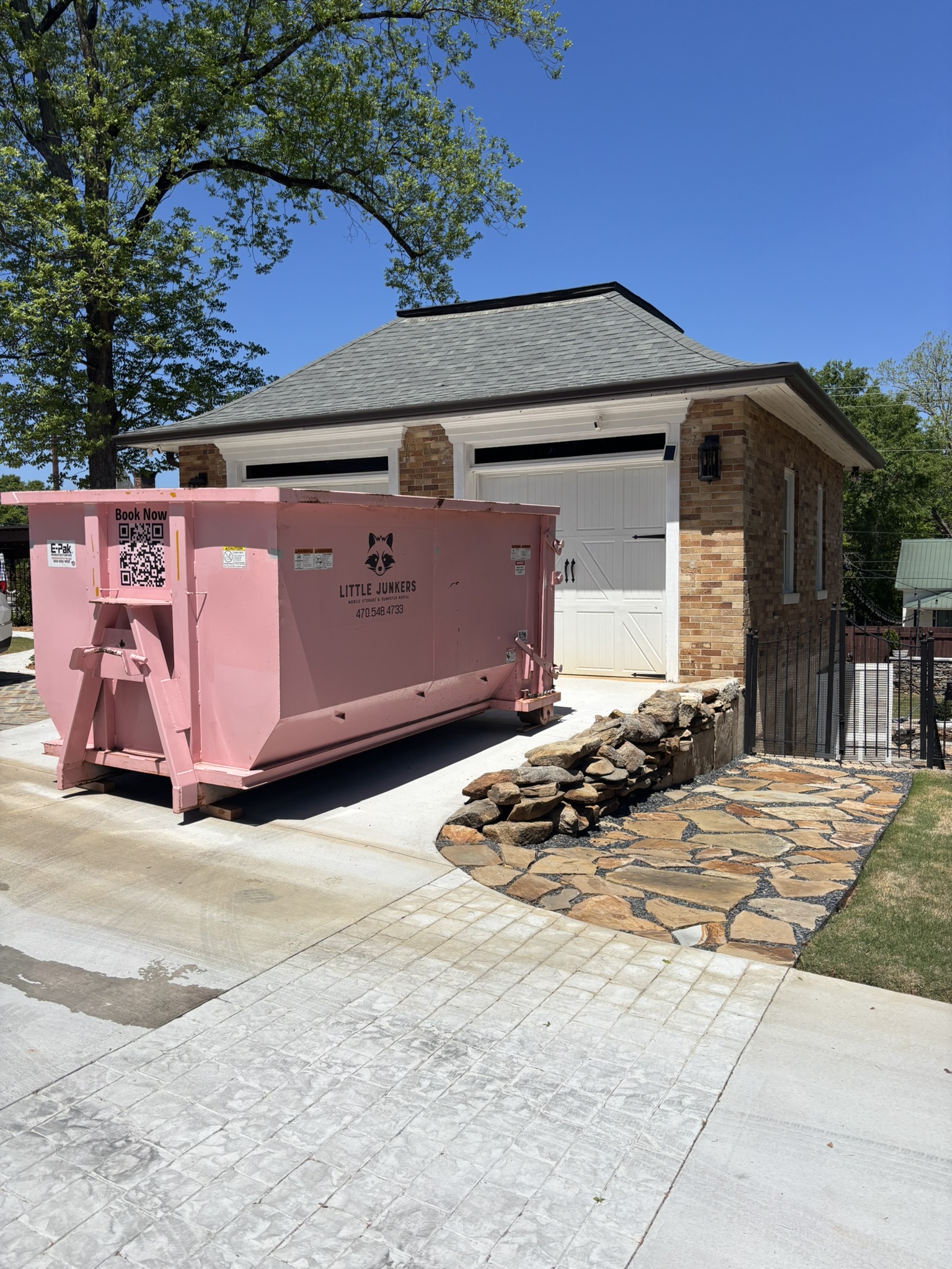 Pink 16-yard Mighty Middler dumpster beside a residential garage in Newnan Georgia