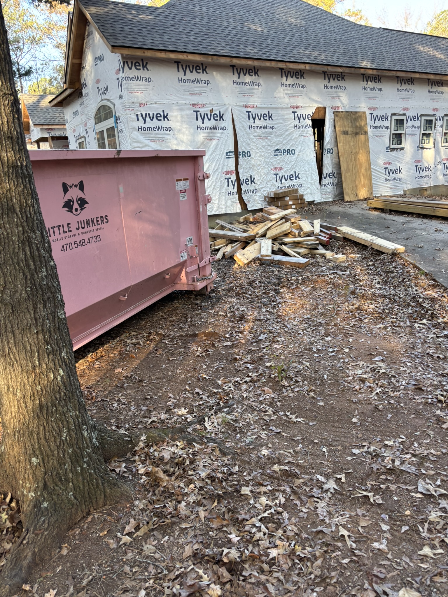 Pink Little Junkers roll-off dumpster outside a residential renovation project