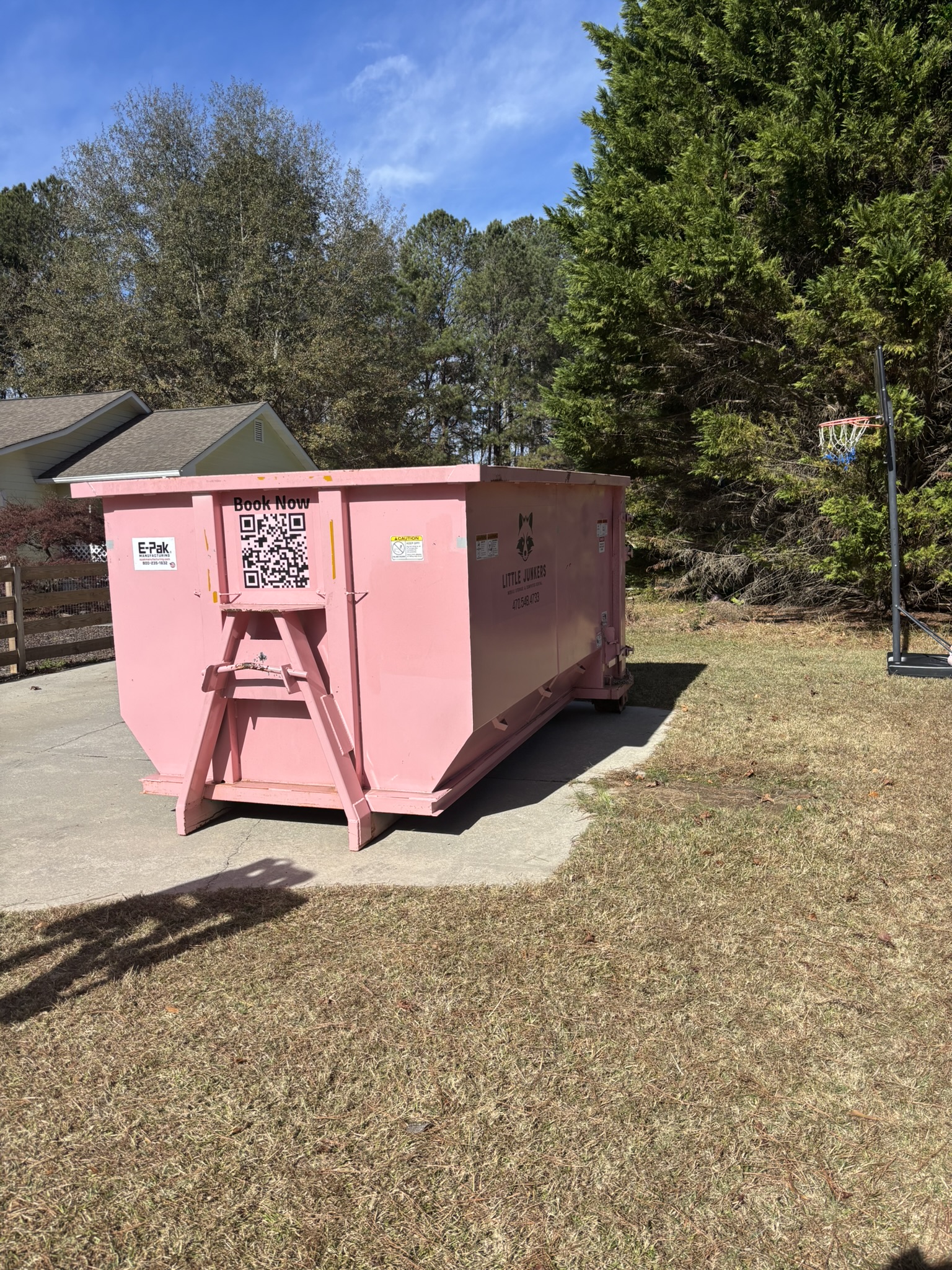 Pink 16-yard Mighty Middler roll-off dumpster at a residential property